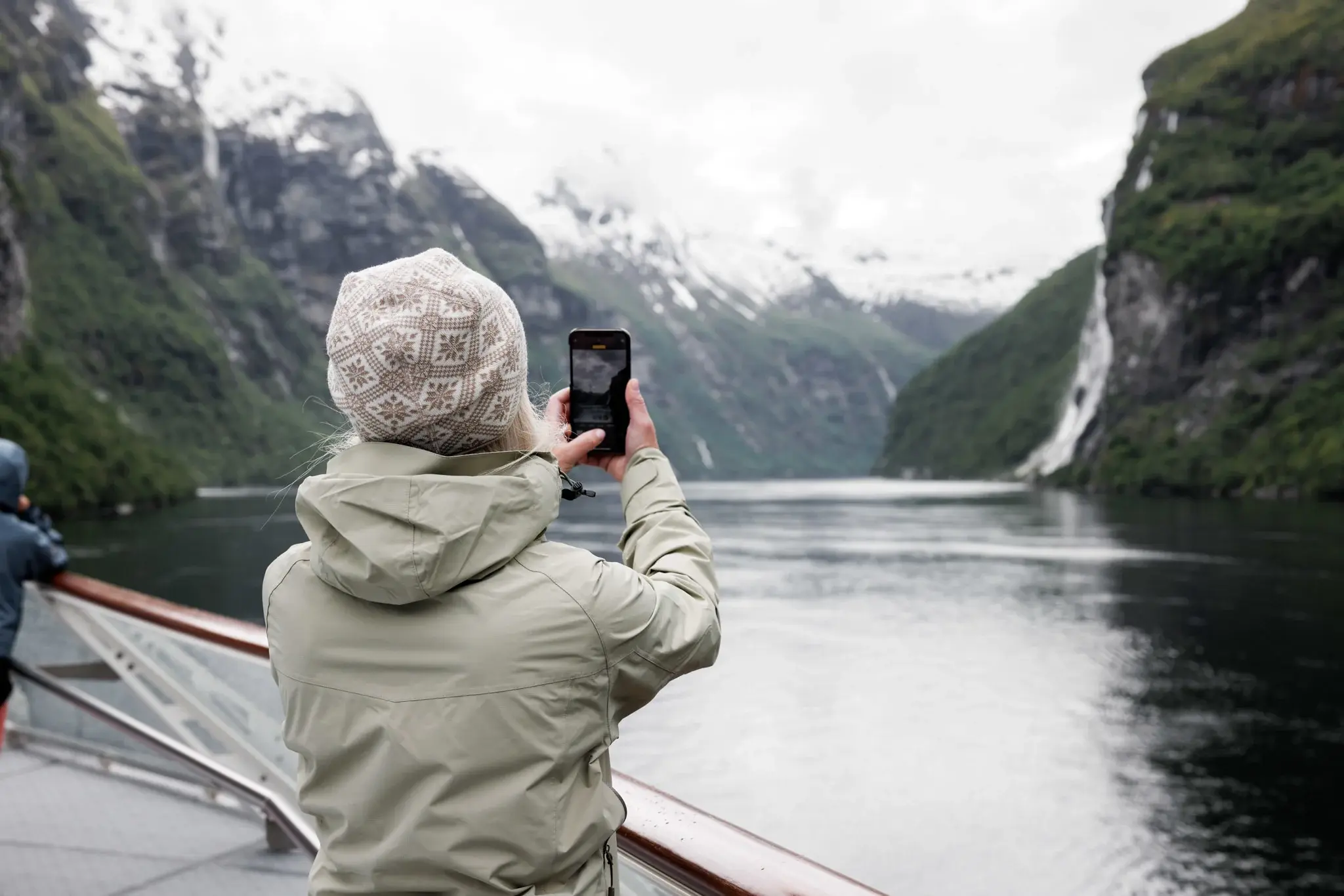 Dame som tar bilde av fossefall i Geirangerfjorden