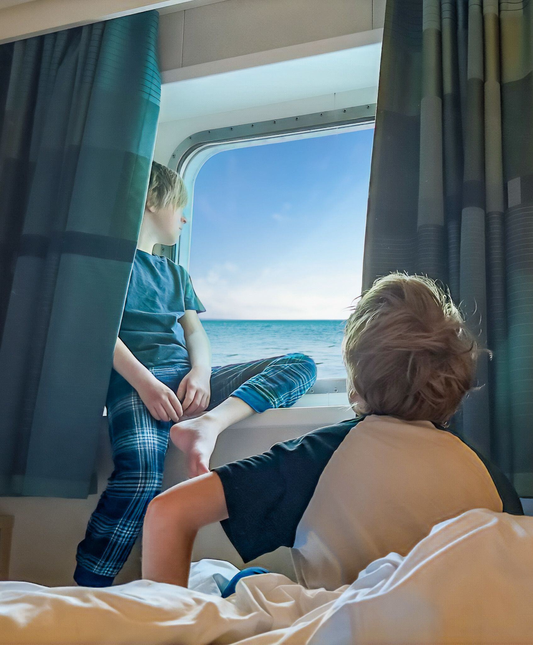 Young boys enjoys the ocean view from their cabin