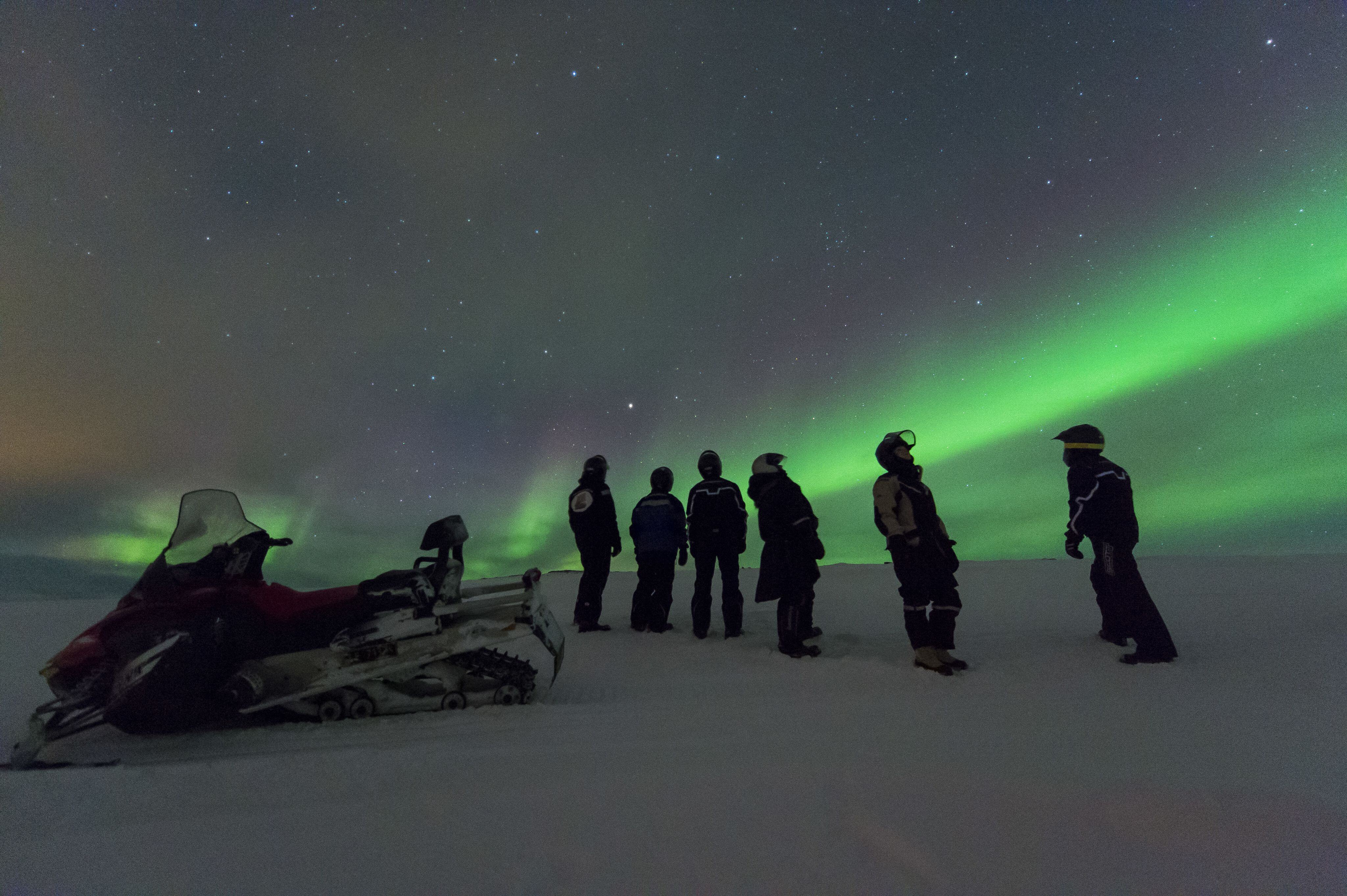 Snowmobile and people under the Northern Lights